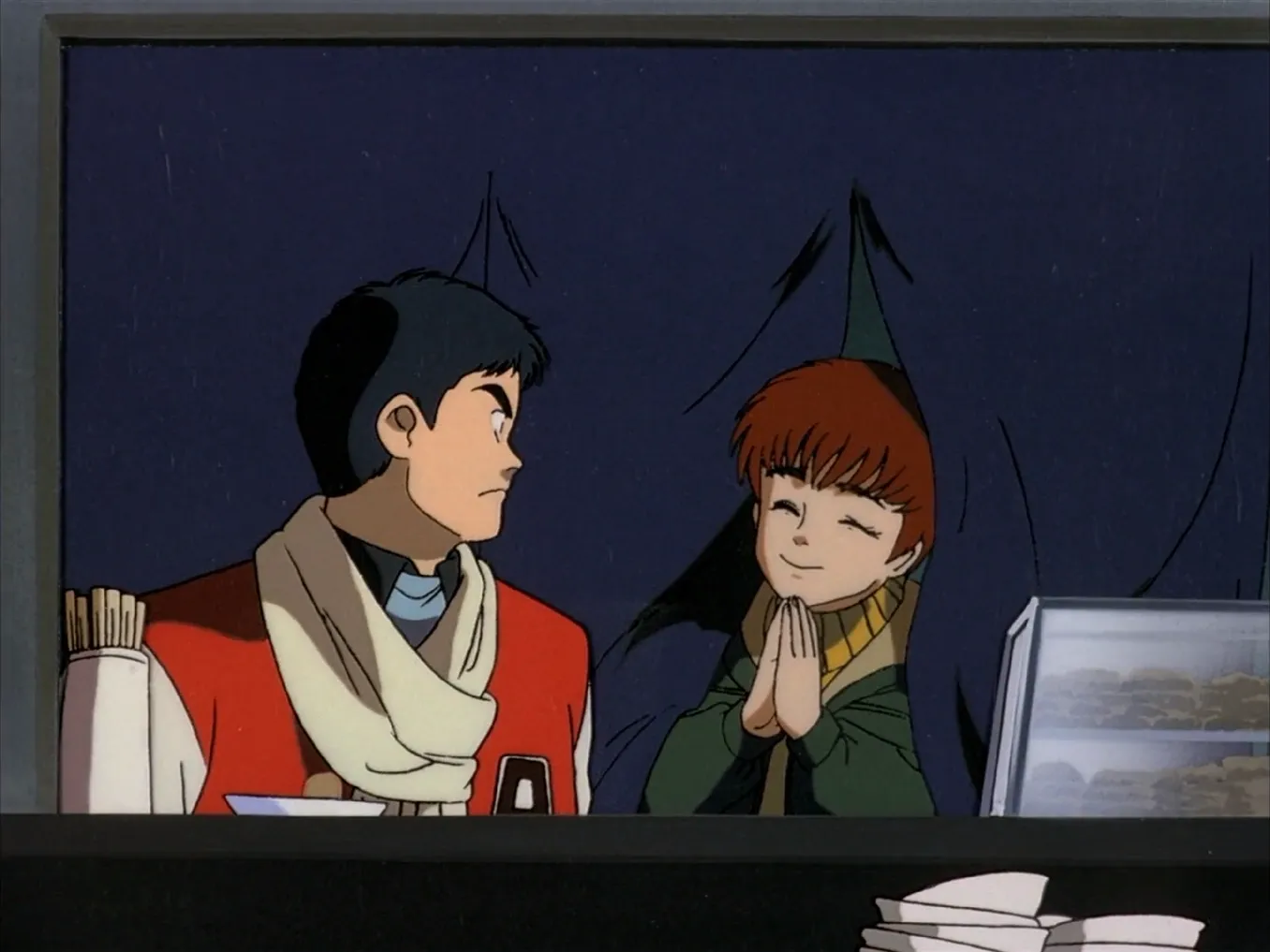 An image from the Patlabor anime, with Asuma sitting in a ramen shop frowning at Noa, who's part way through a curtain, with her eyes closed and hands together in prayer.