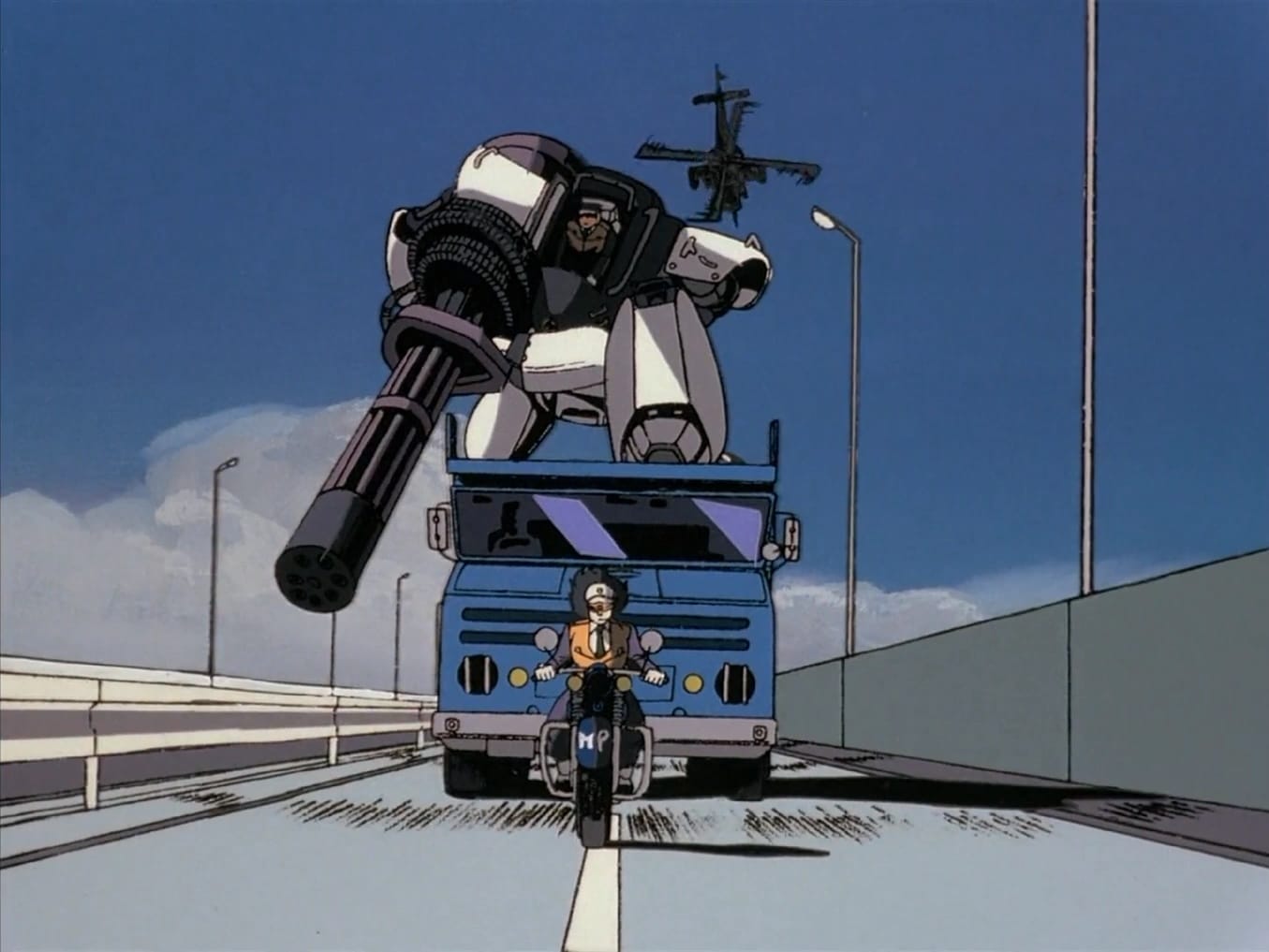 An image from the Patlabor anime of a lady riding a motorcycle in front of a blue flatbed truck carrying a robot holding a huge chaingun on a highway. In the distance flies an attack helicopter.